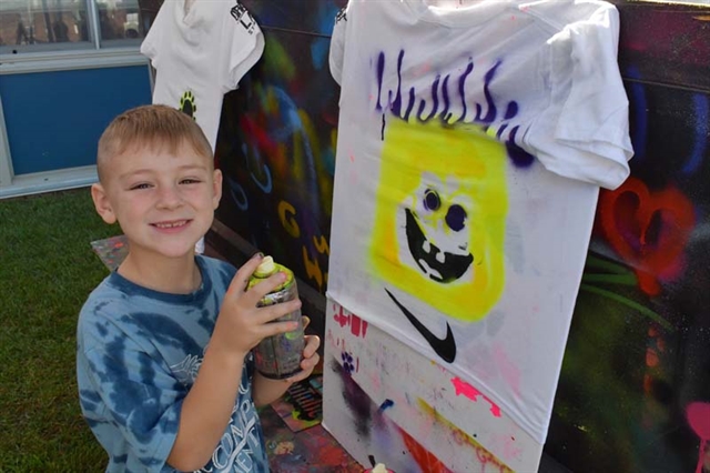 Student smiling next to art project