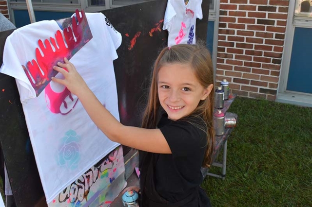 Student smiling next to art project