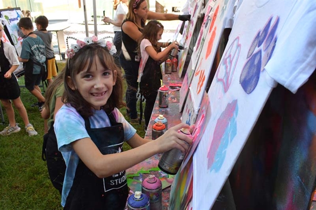 Student smiling next to art project