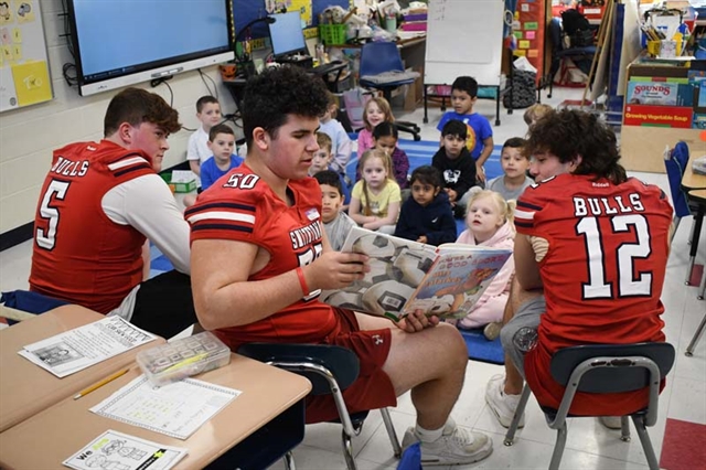 football students reading to kindergarten students