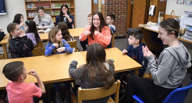 HS students teaching sign language to elementary students