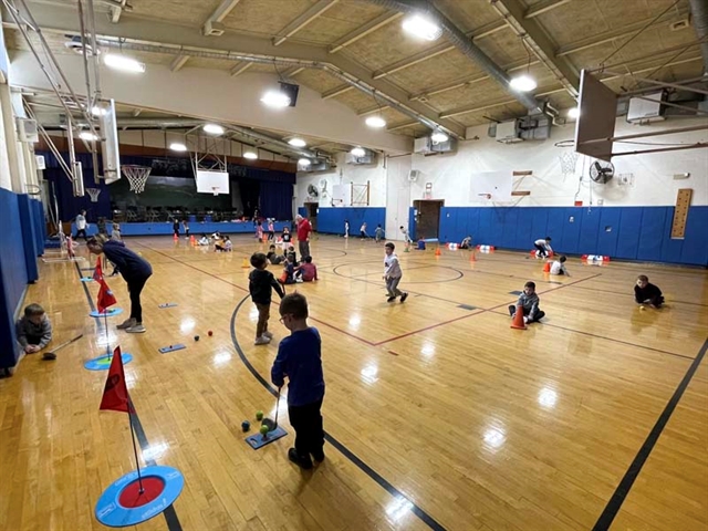 high school students helping younger students play golf