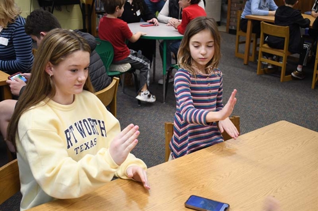 students reading a book using sign language