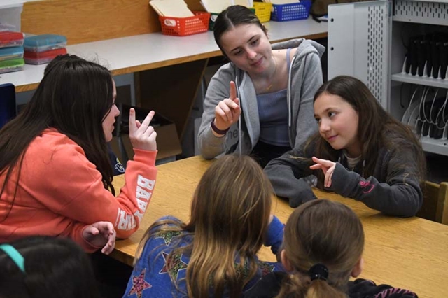 HS students teaching sign language to elementary students