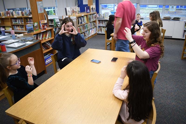 students reading a book using sign language