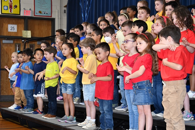 Students singing and dancing while wearing bright colored shirts
